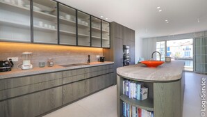 A modern kitchen with a built-in island, a coffee machine, and a bookshelf.