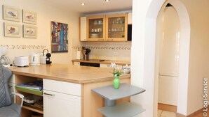 A modern kitchen with wooden cabinets, a countertop, and a small table with a vase.