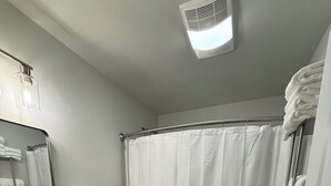 Un bagno con lavandino, water e tenda per la doccia, tutto in bianco.