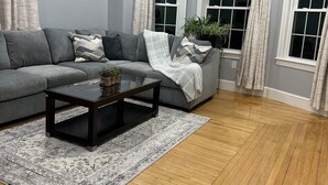 A modern living room with a grey sectional sofa, a dark coffee table, and a patterned rug. - North End Family  (Manchester)