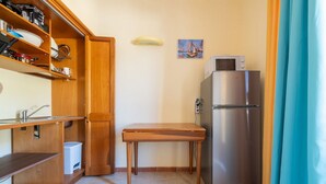 A compact kitchen with a stainless steel refrigerator, wooden cabinets, and a small table. - Ginestre 13 (Is Molas)