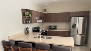 Eine moderne Küche mit Kochinsel, Edelstahlgeräten und Holzbarhocker.