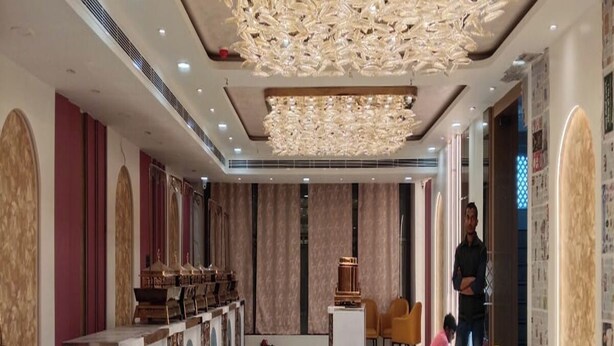 Un amplio vestíbulo de hotel con una larga recepción, una gran araña y un diseño de interiores moderno.
