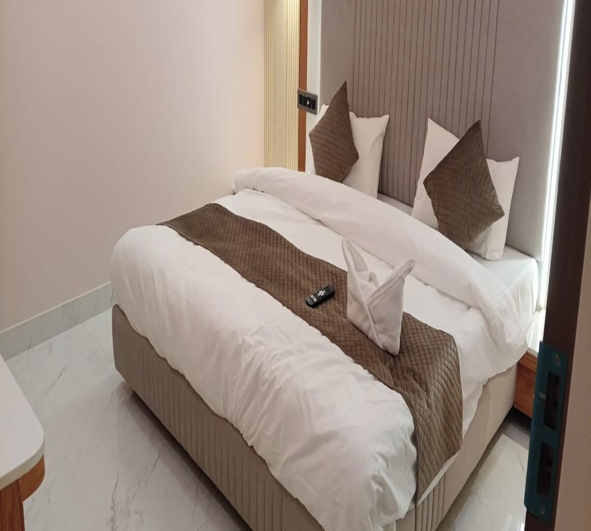 Una cama bien hecha con un edredón acolchado, un control remoto y una almohada.