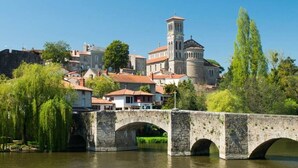 Un puente de piedra sobre un río, con un edificio histórico al fondo.