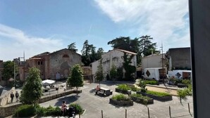 Un patio con edificios de piedra, asientos al aire libre y follaje.