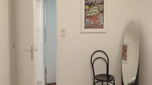 Un dormitorio con cama, una silla, una puerta que da a otra habitación y un cartel en la pared.