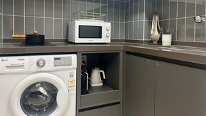 A compact kitchen with a microwave, a washing machine, and a kettle. - YEONSAN THE STAY (Busan)