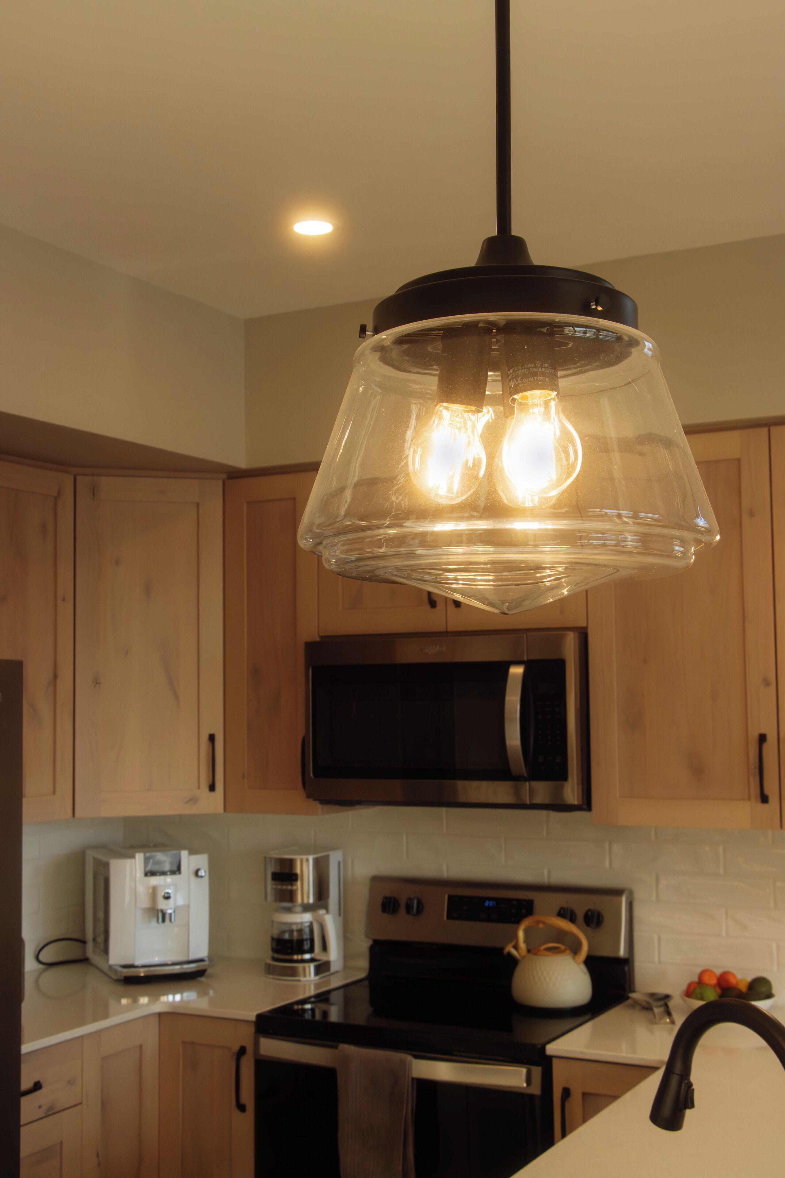 A kitchen with wooden cabinets, a microwave, a stove, a kettle, and a coffee maker.
