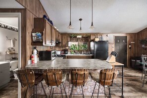 A kitchen with a central island, wooden cabinets, a refrigerator, and a sink. - Zen Vibe w/Hot Tub, Fireplace, Grill, Deck & More (Hedgesville)