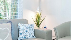 A living room with a sofa, a side table, and a potted plant.