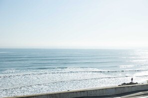 A coastal view with a concrete barrier and a person standing on it. - Hampton Tides | Ocean Views | Top Floor Balcony (Hampton)