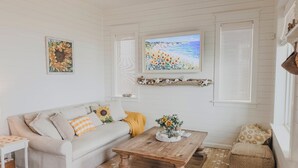 A cozy living room with a sofa, coffee table, and a painting of a beach scene.