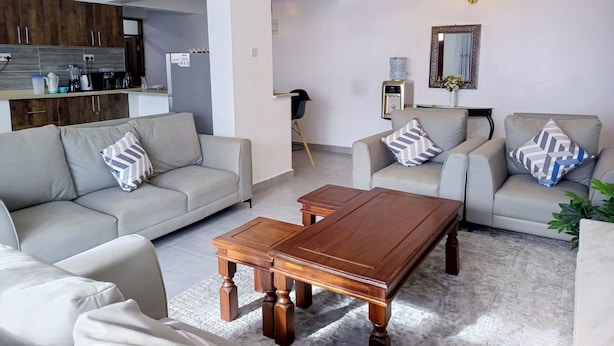 Una sala de estar moderna con un sofá, sillones y una mesa de centro de madera.