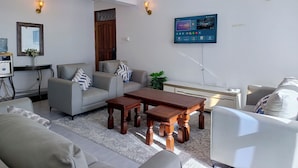 Una sala de estar moderna con televisor de pantalla plana, asientos cómodos y un ventilador de techo.