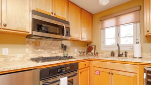 A kitchen with wooden cabinets, a stainless steel stove, and a microwave. - Casita Gomez- Courtyard - Quiet - Railyard - 1BR (Santa Fe)
