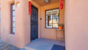 A building entrance with a black door, a window, and a small table with a potted plant. - Casita Gomez- Courtyard - Quiet - Railyard - 1BR (Santa Fe)