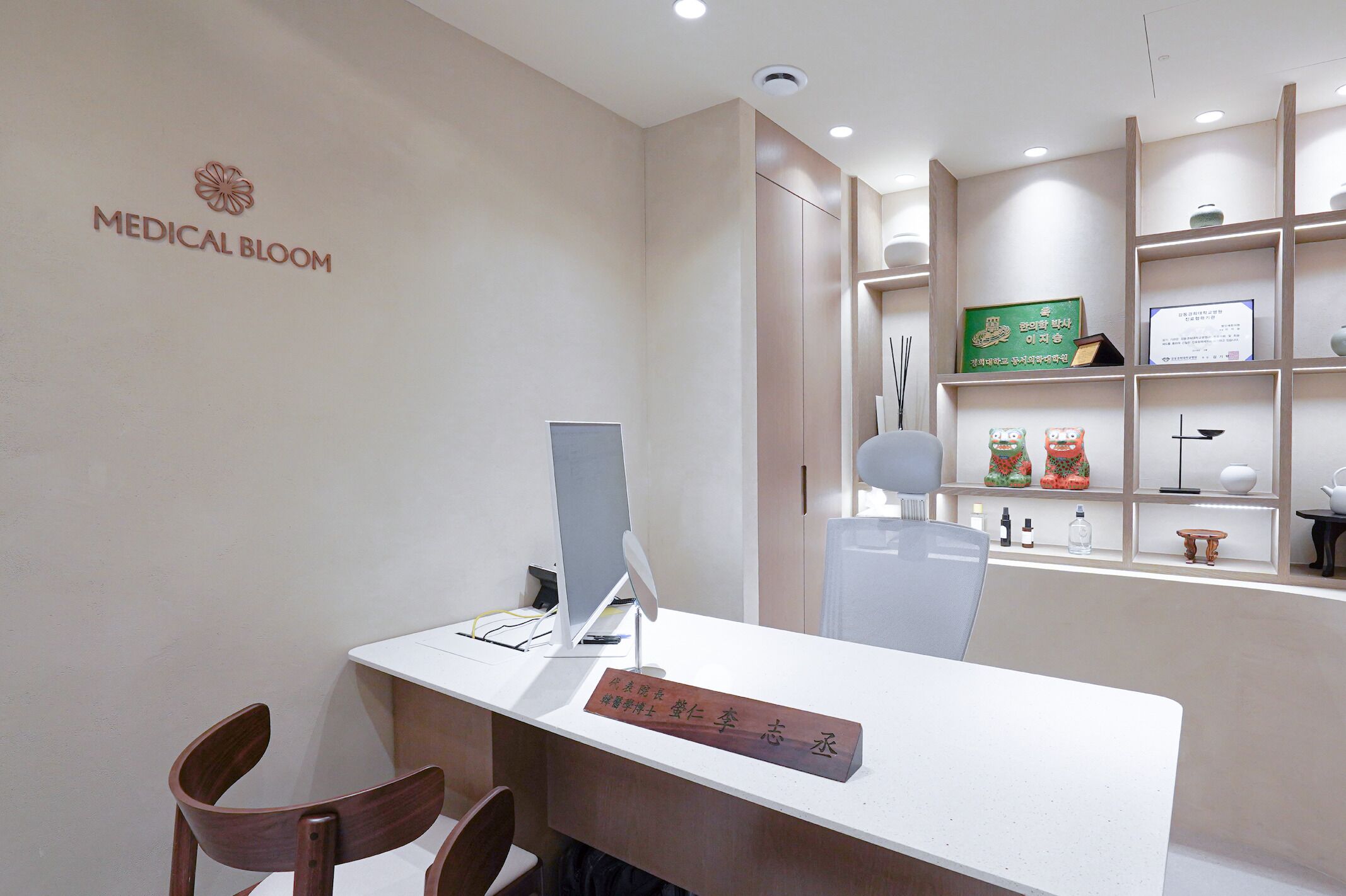 A reception desk with a sign reading 'Medical Bloom,' a computer, a chair, and a shelf with various items including a framed certificate.