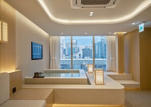 A modern hotel room with a large window, a flat-screen TV, a bathtub, and a reception desk. - UH Suite The Coex (Seoul)