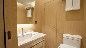 A modern bathroom with a wooden vanity, a sink, and a toilet.