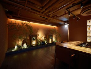 A modern bar area with a wooden counter, two large speakers, and a wall-mounted plant display. - UH Suite The Coex (Seoul)