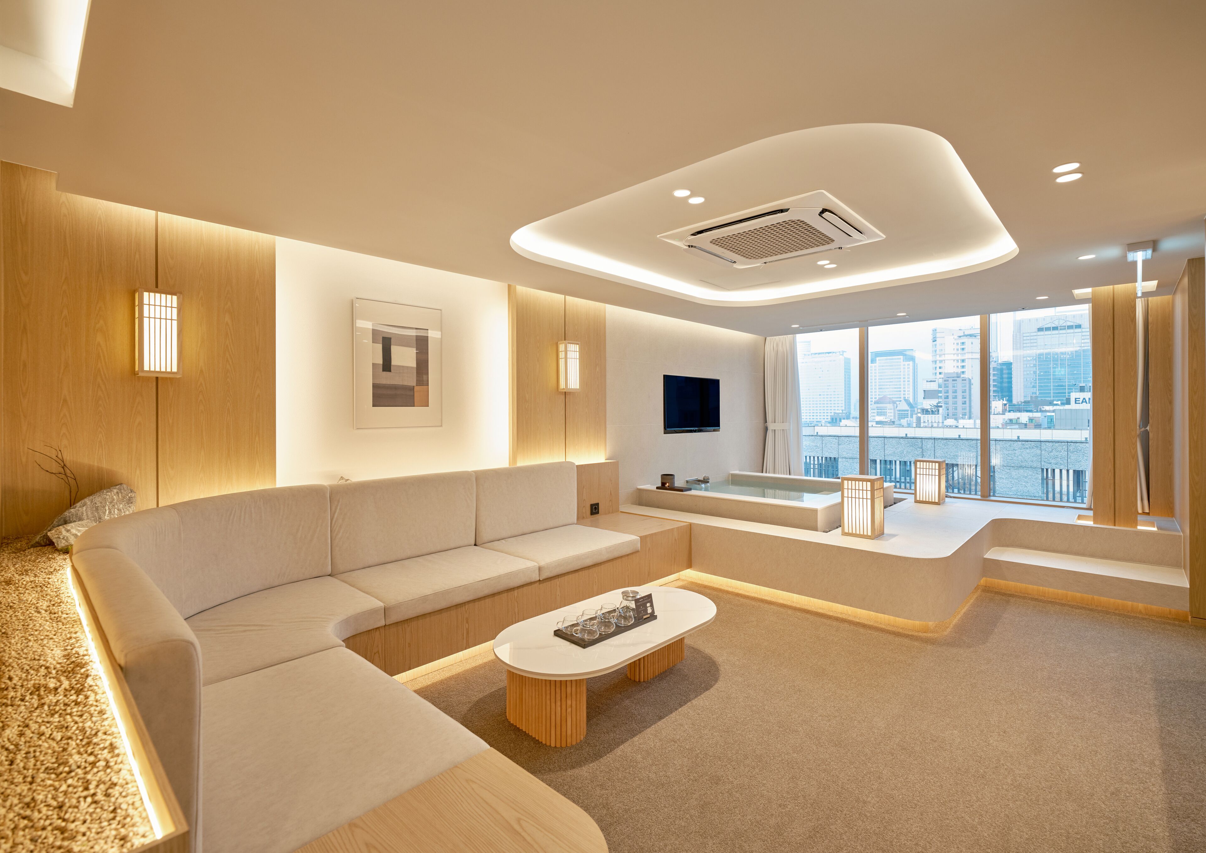 Una sala de estar moderna con un sofá, una mesa de centro, un televisor y vistas a la ciudad.