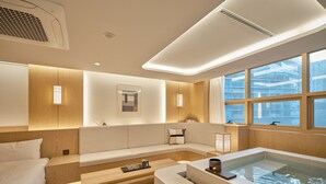 A modern bathroom with a bathtub, a bench, and a window providing a view of the outside. - UH Suite The Coex (Seoul)