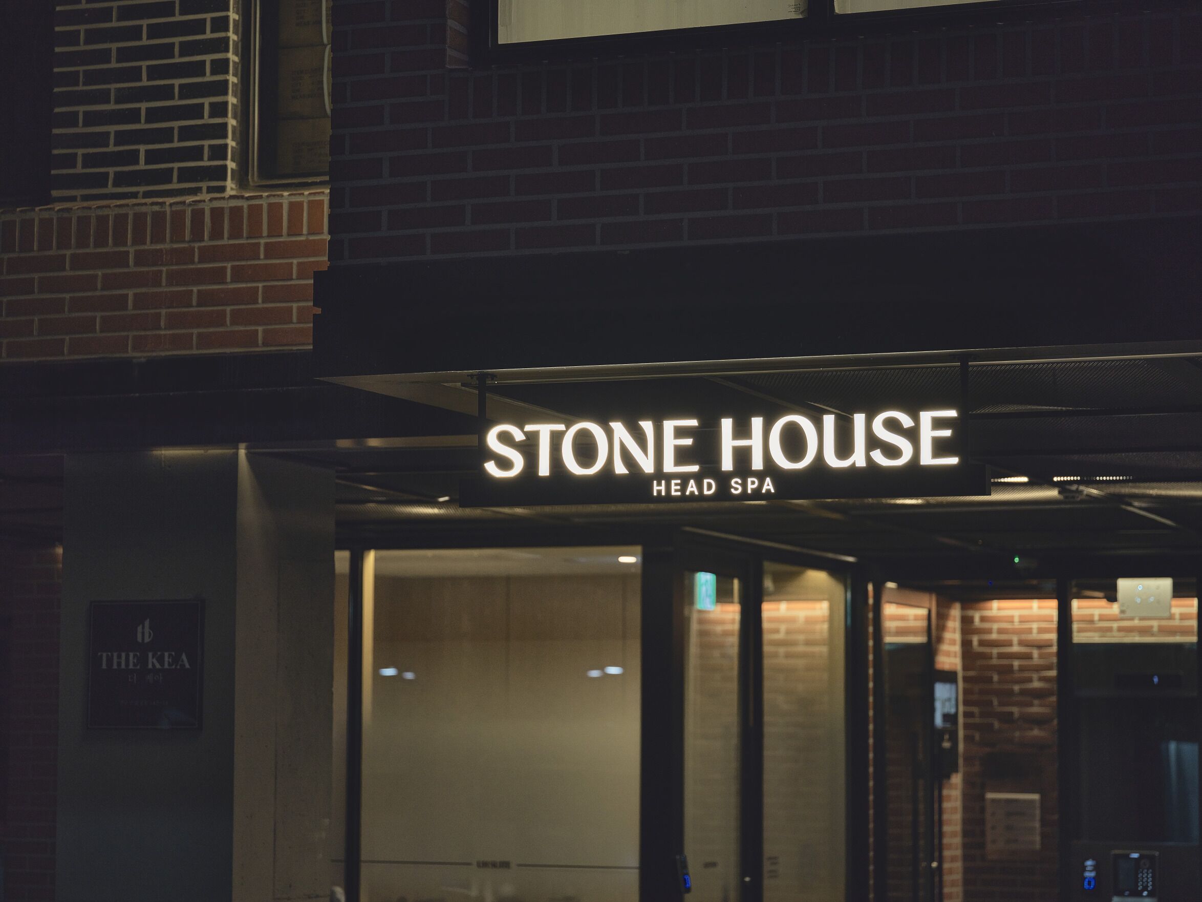 The exterior of Stone House Head Spa, featuring a prominent illuminated sign and a glass entrance.