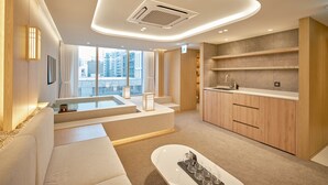 A modern hotel room with a large window, a bathtub, a kitchen area, and a seating area. - UH Suite The Coex (Seoul)