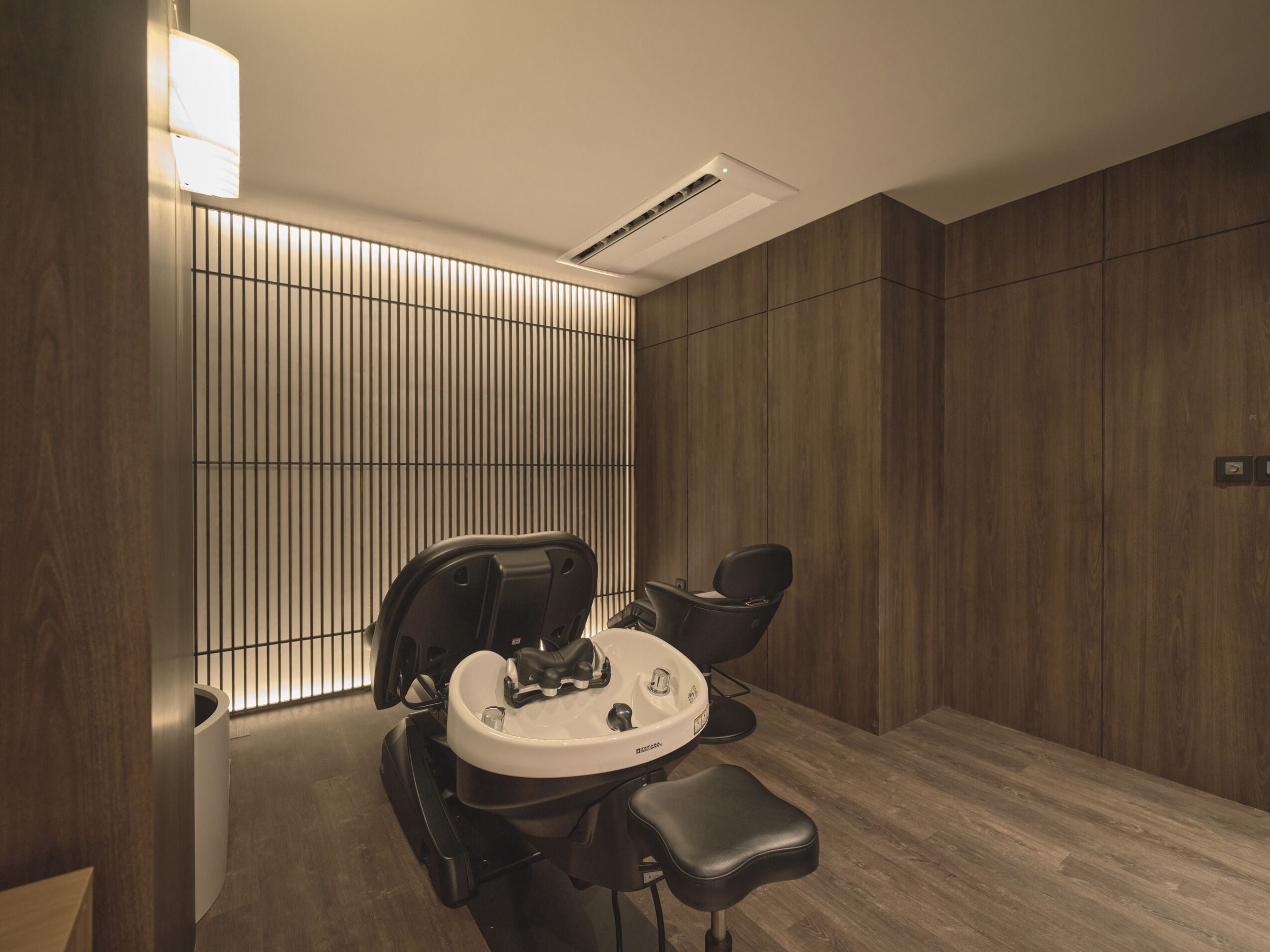 A modern bathroom with a large mirror, a sink, and a chair.