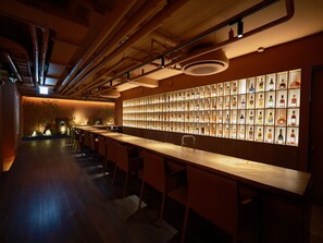 A bar area with a long counter, multiple stools, and a wall of neatly arranged liquor bottles. - UH Suite The Coex (Seoul)