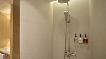 A shower with a handheld showerhead and a handheld hose, a towel rack, and three bottles of shampoo and conditioner on the wall.