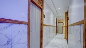 A corridor with marble flooring and wooden paneling, leading to a door with a number sign. - HOTEL ARTS INTERNATIONAL  (Mumbai)