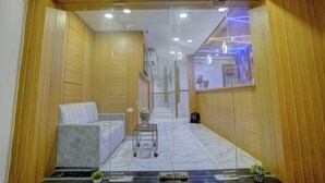 A modern hotel lobby with wooden paneling, a sofa, a small table with a vase, and a marble floor. - HOTEL ARTS INTERNATIONAL  (Mumbai)