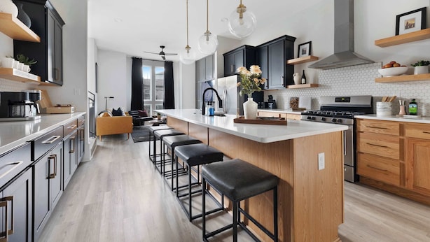 Una cocina moderna con una isla grande, taburetes de bar e iluminación colgante.