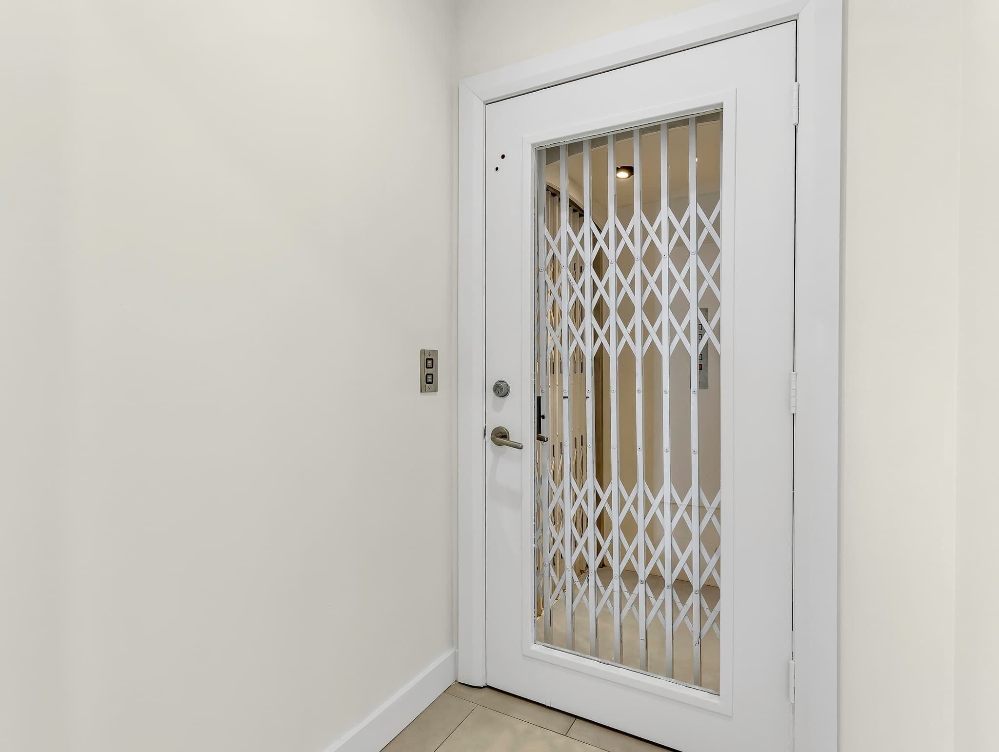 A white door with a metal security grille and a keyhole.