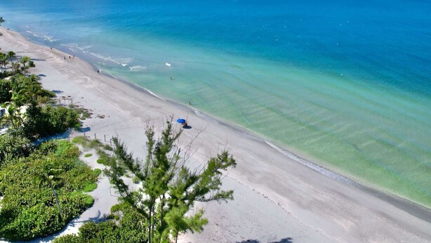 A beach with clear turquoise water and a sandy shore. - Casa Captiva - Ground Level 5 BR Luxe Villa with Grotto Pool, Steps to Beach (Captiva)