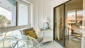 Une pièce avec une table en verre, une chaise dotée d’un coussin jaune, une lampe et une vue sur l’extérieur.