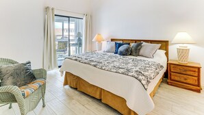 Une chambre à coucher avec un lit, une table de chevet, une chaise et une fenêtre avec des rideaux.