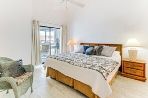 A bedroom with a bed, a nightstand, a chair, and a window with curtains.