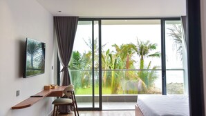 A modern bedroom with a large window, a bed, a desk with a chair, and a TV mounted on the wall.