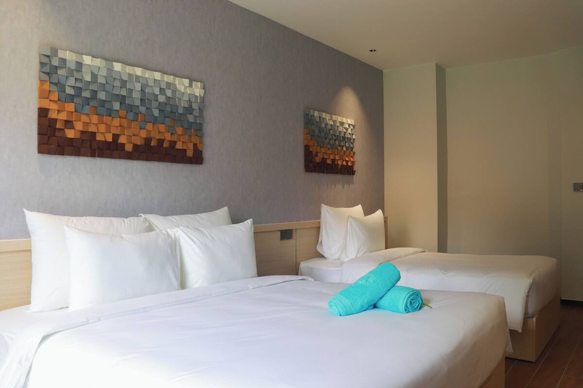 Habitación de hotel con dos camas, ropa de cama blanca y dos obras de arte abstractas en las paredes.