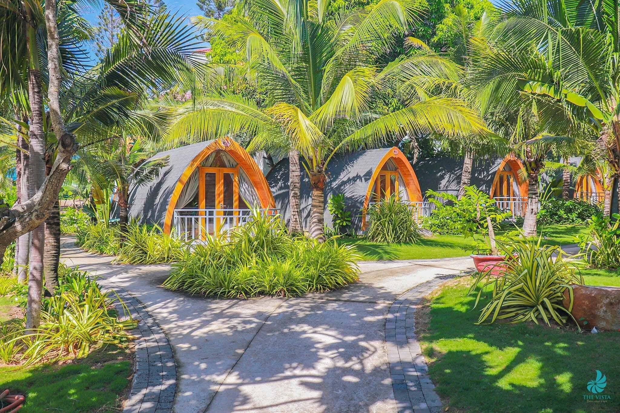 Un sendero conduce a una hilera de alojamientos tipo casa en los árboles, rodeados de exuberante vegetación.