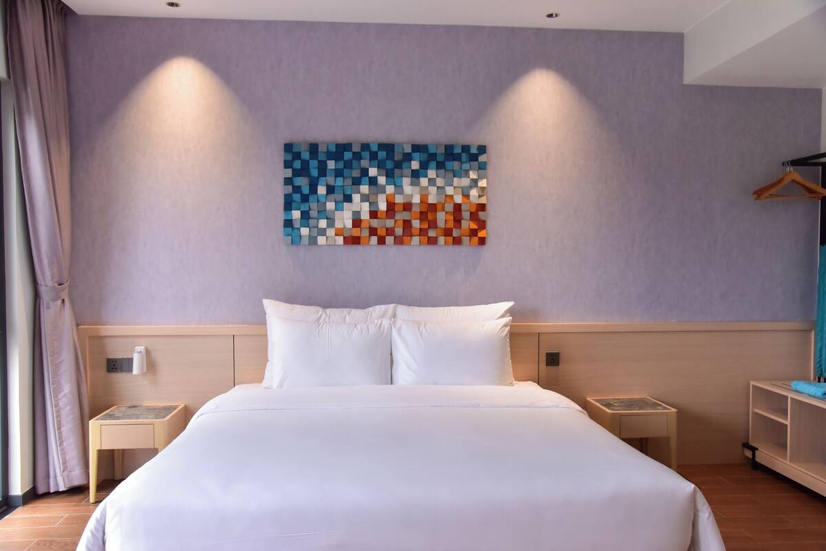 Una habitación de hotel con una cama grande, dos mesitas de noche, una obra de arte en la pared y un armario.