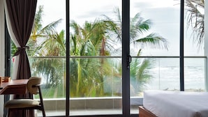 A room with a large window overlooking palm trees and the ocean.