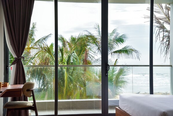 Una habitación con un ventanal grande que da a palmeras y al océano.