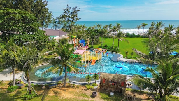 A resort with a large swimming pool, water slides, and a view of the ocean.