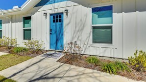 Una casa moderna con puerta azul, revestimiento blanco y techo azul.