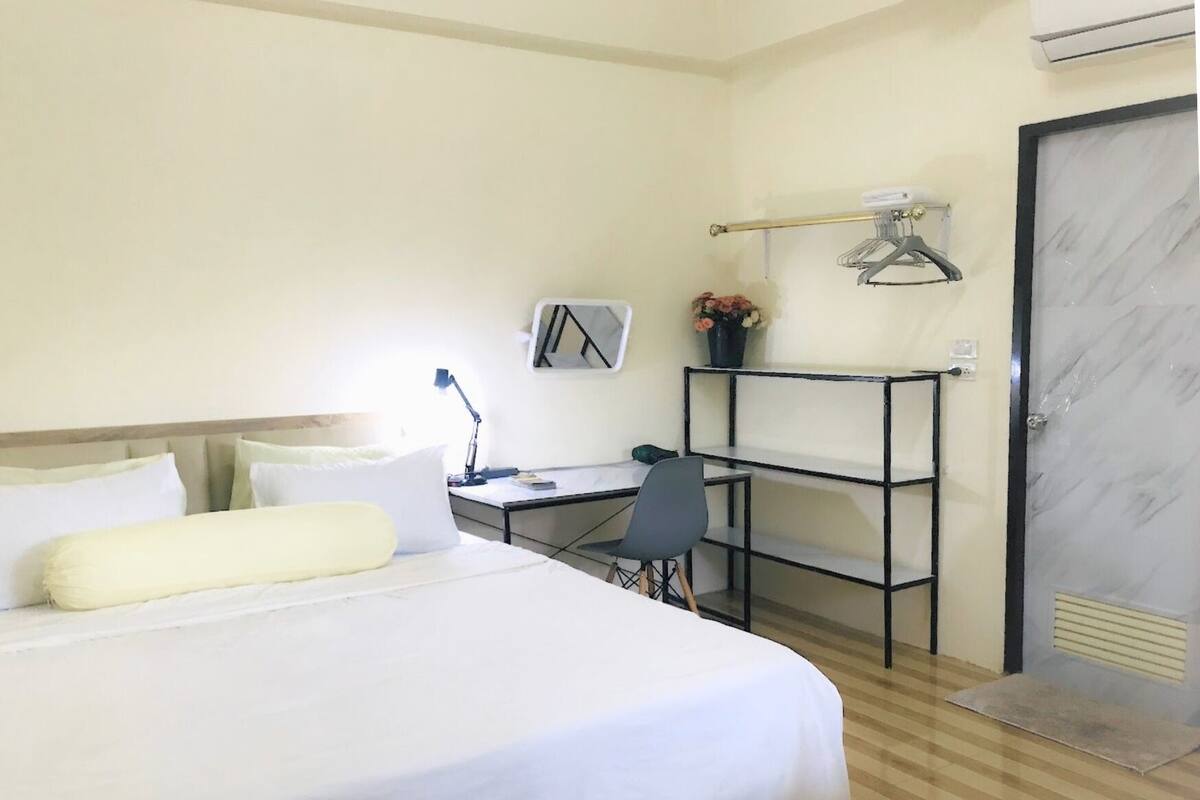 Una habitación de hotel con cama, escritorio, silla y armario.