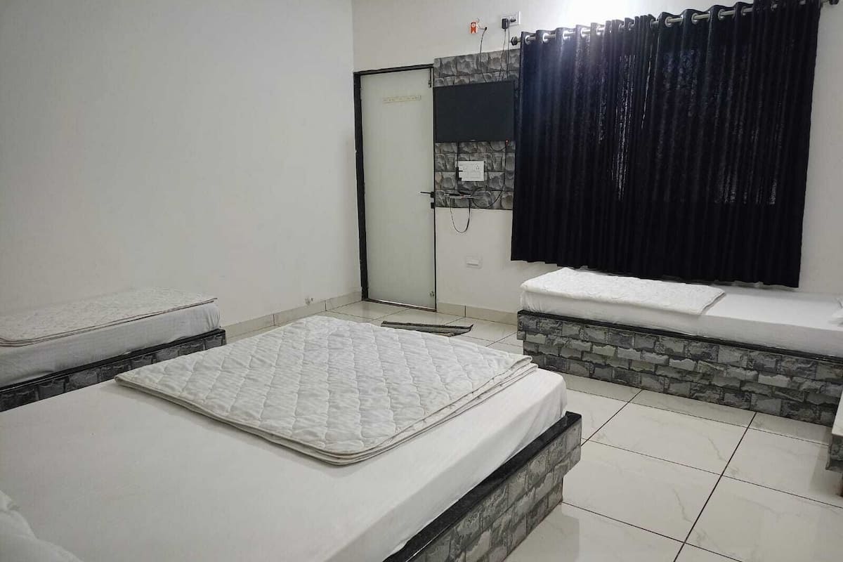 A bedroom with a bed, a bench, a shower area, and a tiled floor.